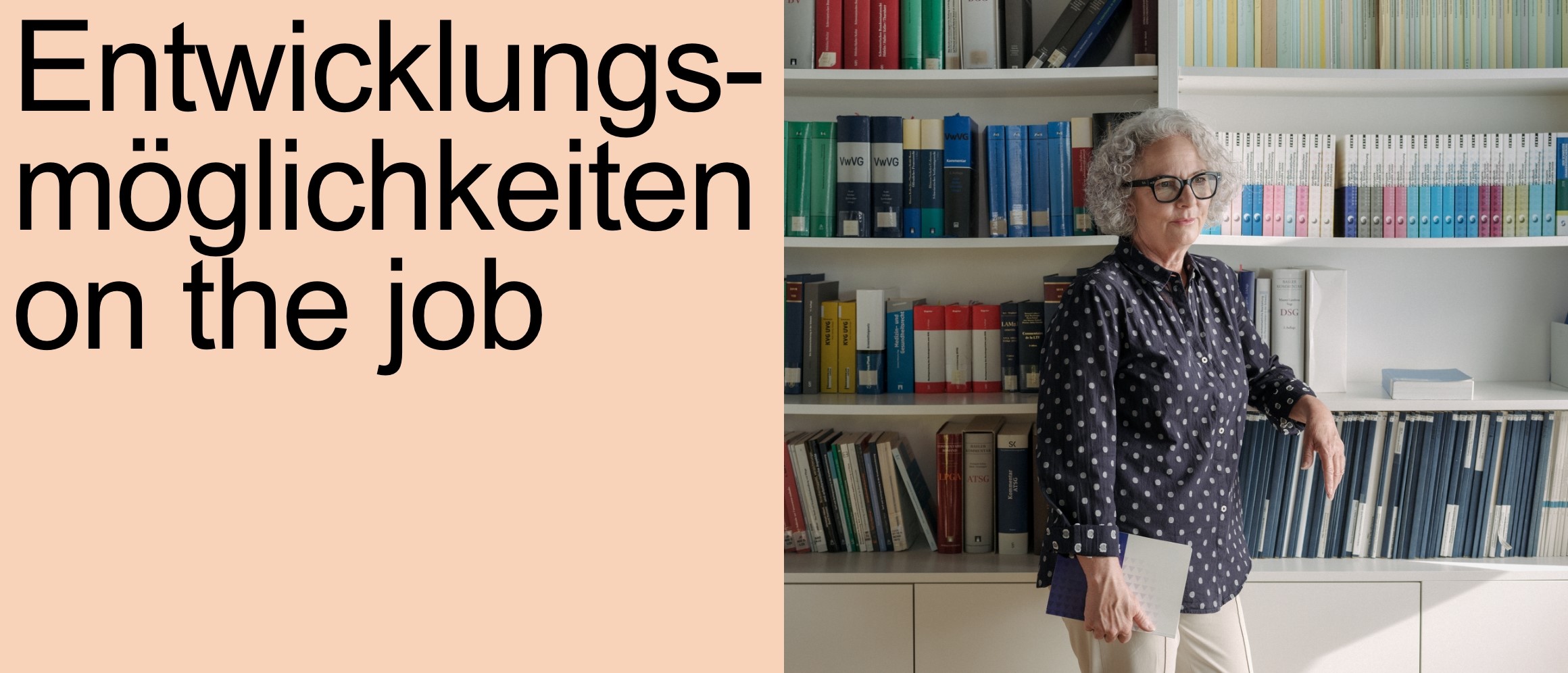 Entwicklungsmöglichkeiten on the job [eine Frau mit grauen, gelockten Haaren bis zum Kinn lehnt sich mit einem Arm an ein grosses Bücherregal an. Sie trägt eine dunkelblaue Bluse mit weissen Punkten und eine cremefarbene Hose sowie eine schwarze Brille mit dickem Rahmen. In der anderen Hand hält sie ein Buch und schaut nach links, wahrscheinlich aus dem Fenster.]