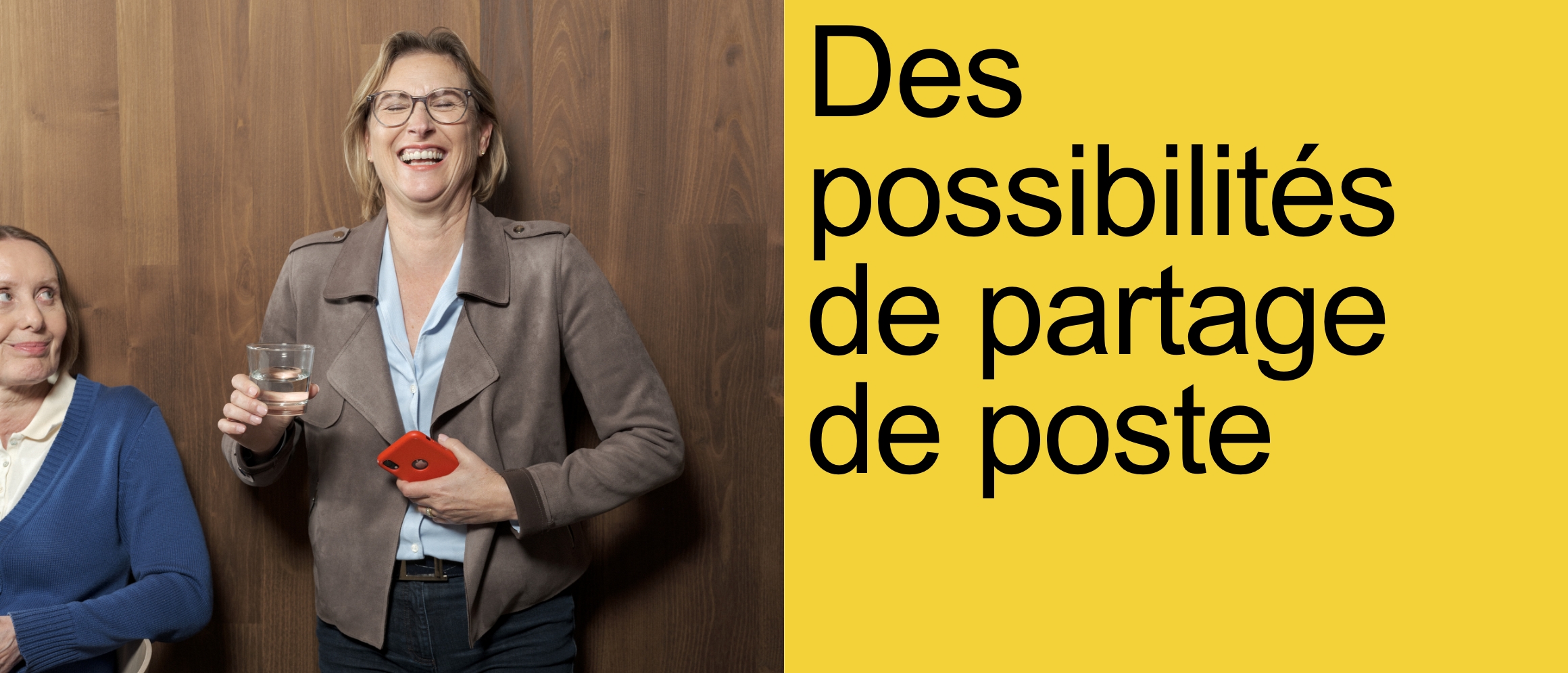 Des possibilités de partage de poste [deux femmes sont devant un mur en bois sombre. L'une des femmes est assise sur une chaise. Elle porte un cardigan bleu et un chemisier blanc en dessous. Elle sourit légèrement et regarde l'autre femme debout, un peu perplexe. La femme debout a les yeux fermés et rit.]